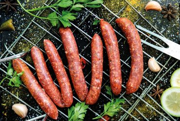Raw sausages merguez, on a black background, with spices on the